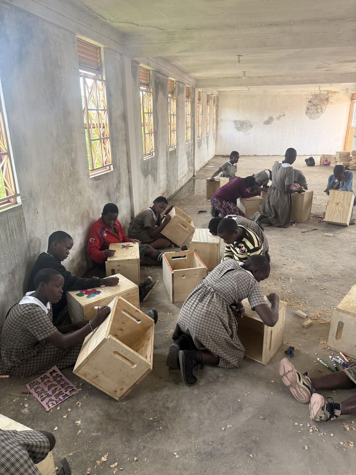 Ugandan students building wooden crates as part of a construction skills project